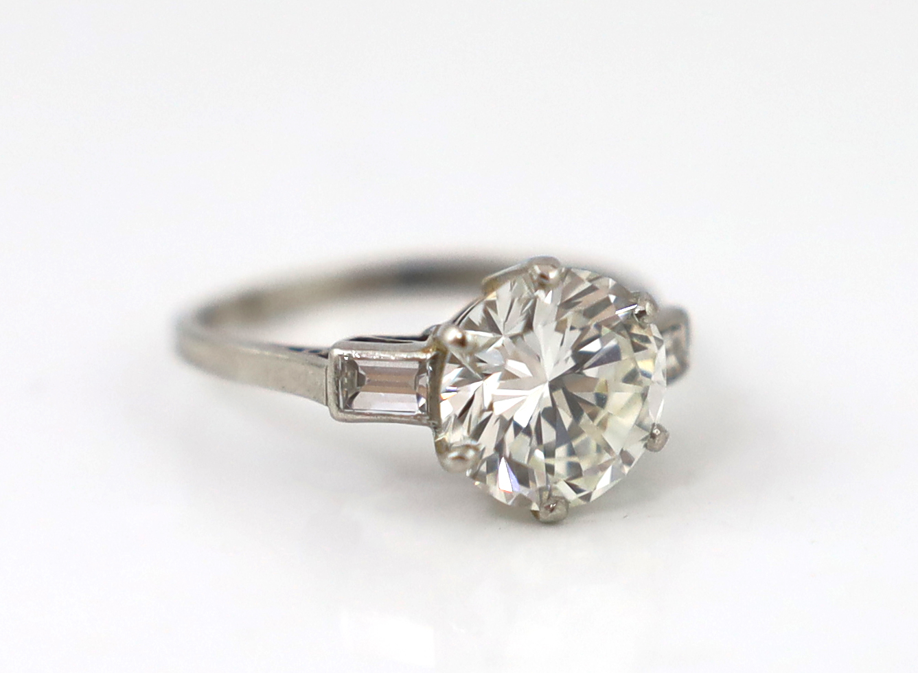 A good platinum or white gold set single stone diamond ring, with two stone baguette cut diamond set shoulders